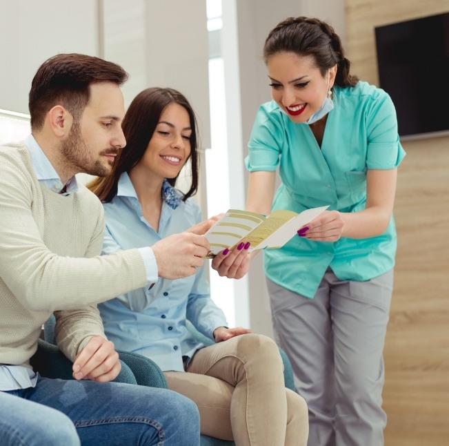 Dental team member showing a pamphlet to two patients