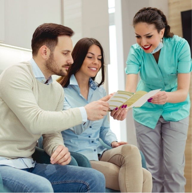 Dental team member showing pamphlet to two patients