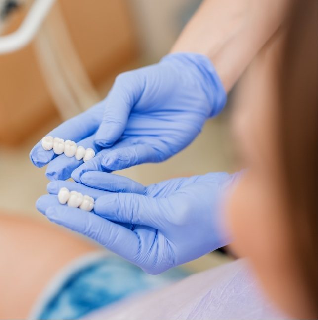 Dentist holding two dental bridges prior to placement