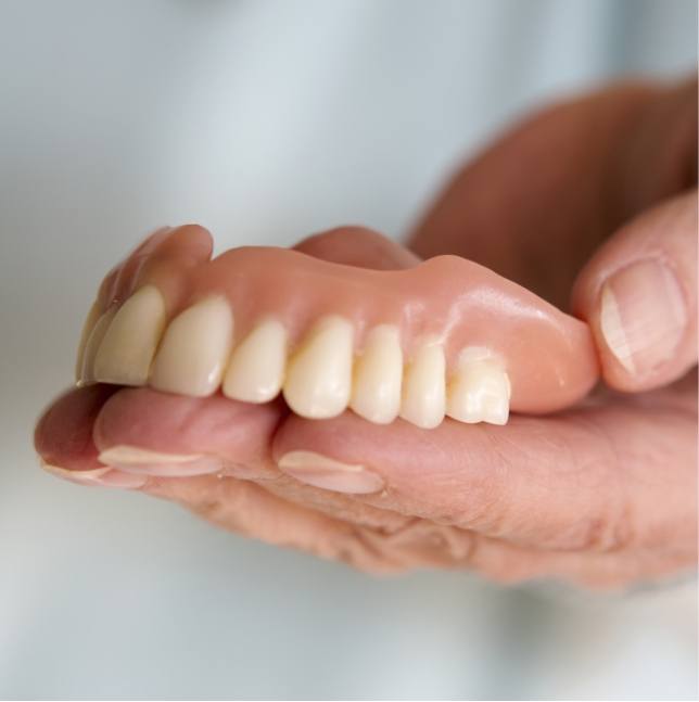 Hand holding full denture