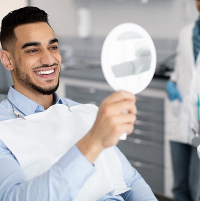 a man looking into a handheld dental mirror