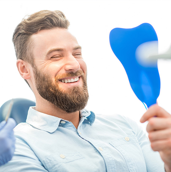 A dental patient looking at his smile in mirror